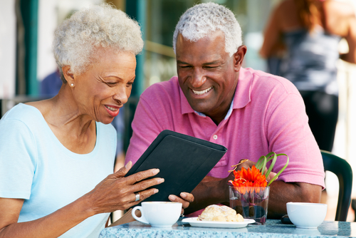 elderly couple looking at ipad in a cafe